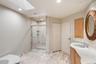Bathroom featuring a glass-enclosed shower with integrated shelving, a skylight, recessed lighting, and stone-finish flooring