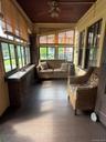 Enclosed porch featuring dark wood-finish flooring, a wood-paneled ceiling, and multiple windows with natural light