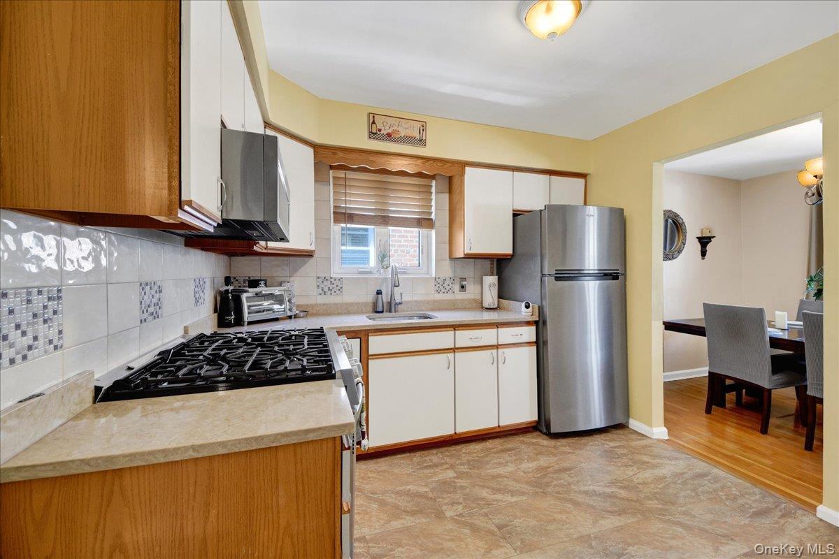 Kitchen featuring a gas range, stainless steel refrigerator, and tiled backsplash