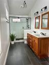 Bathroom featuring toilet, double vanity, a sink, and a shower stall