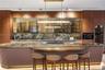 Gourmet kitchen featuring oversized curved island with book-matched stone countertop, fluted base, gas cooktop, bronze-framed glass upper cabinets, fu