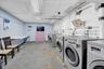 Dedicated laundry room featuring multiple front-loading washing machines, durable concrete flooring, and ample overhead strip lighting