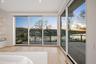 Unfurnished bedroom with access to outside, a water view, and light hardwood / wood-style floors