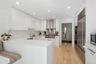 Kitchen with white cabinets, wall chimney exhaust hood, kitchen peninsula, and sink