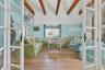 Living room with high vaulted ceiling, beam ceiling, light wood-style flooring, and french doors