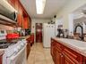 Galley kitchen featuring wood-finish cabinetry, stone-look countertops, and tile flooring