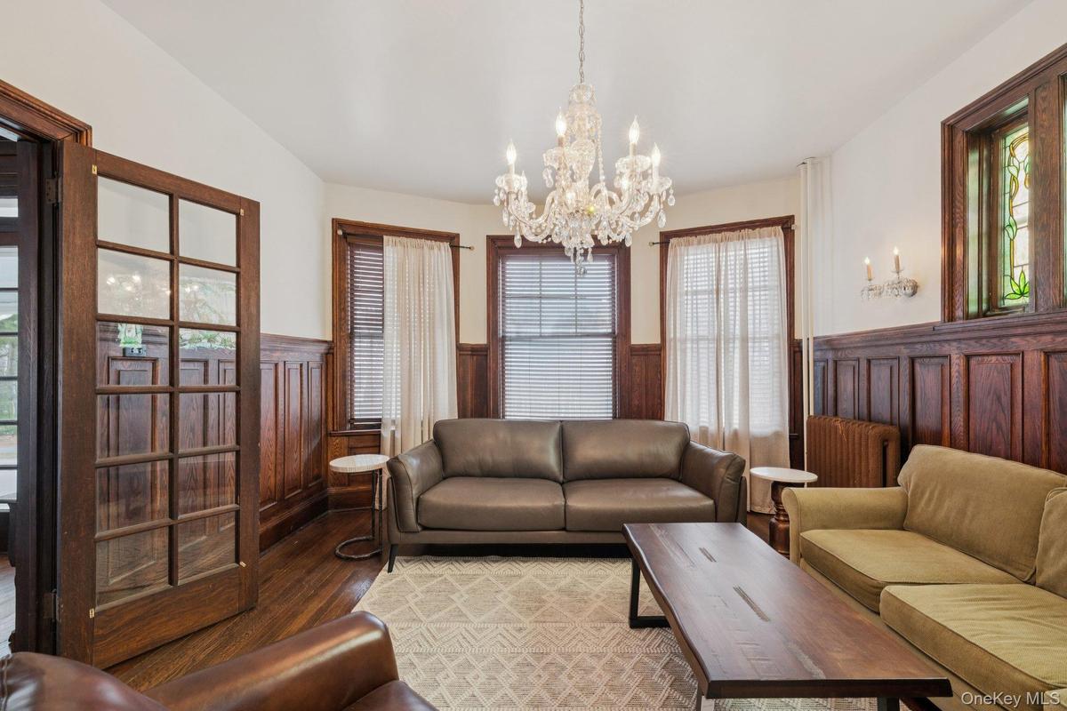 Living room featuring a wainscoted wall, wood finished floors, a chandelier, and radiator