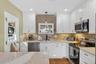 Kitchen with appliances with stainless steel finishes, healthy amount of natural light, white cabinets, and recessed lighting