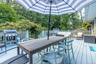 Wooden deck with outdoor dining space, view of scattered trees, and grilling area