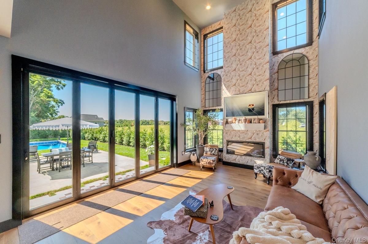 Living area with a fireplace, wood finished floors, and a high ceiling