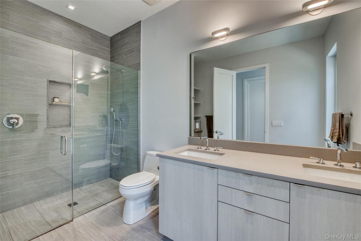 Bathroom with toilet, an enclosed shower, and vanity