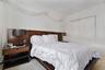 Bedroom featuring a built-in wood-finish headboard, white walls, and a sliding door closet