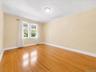 Hardwood flooring, dual windows, white trim, light-colored walls, and a ceiling-mounted light fixture
