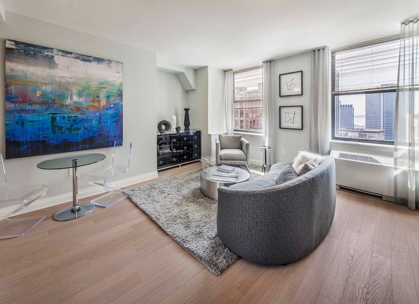 Modern 1 bedroom with open L shaped kitchen featuring stainless steel appliances and stone counters, an in unit washer dryer, wood floors and an oversized bedroom.