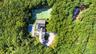 Extensive grounds featuring a tennis court, a swimming pool with a stone patios, a multi-level residence with a separate cottage and gravel driveway.