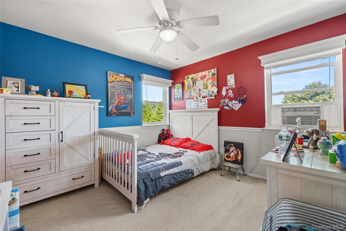 Spacious room featuring carpeting, two windows with white trim, and a ceiling fan