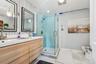 Full bathroom with double vanity, a stall shower, and light marble finish flooring