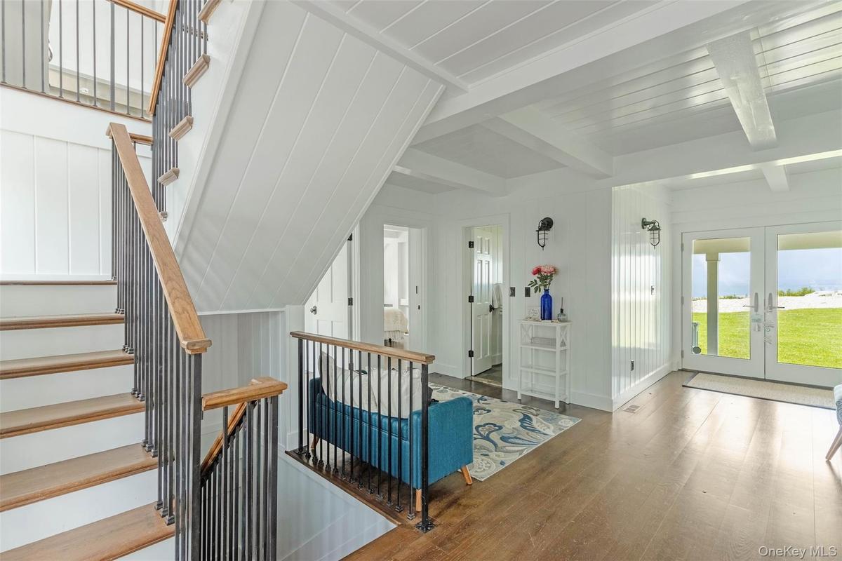 Stairs featuring wood finished floors, french doors, and beam ceiling