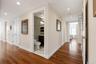 Hardwood flooring extends throughout this interior hallway, featuring recessed lighting and a white trim package