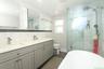 Modern bathroom featuring a double vanity with gray cabinetry, brushed nickel hardware, and a white countertop
