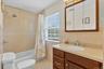 Bathroom featuring a built-in vanity and integrated sink, a tiled shower/tub combination, a window with blinds, and a mirrored medicine cabinet