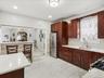 Kitchen featuring freestanding refrigerator, light finish flooring, gas range oven, backsplash, and dark wood finish cabinets