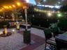 Landscaped outdoor area featuring gravel ground cover, brick paver pathways, perimeter hedging, and built-in patio lighting