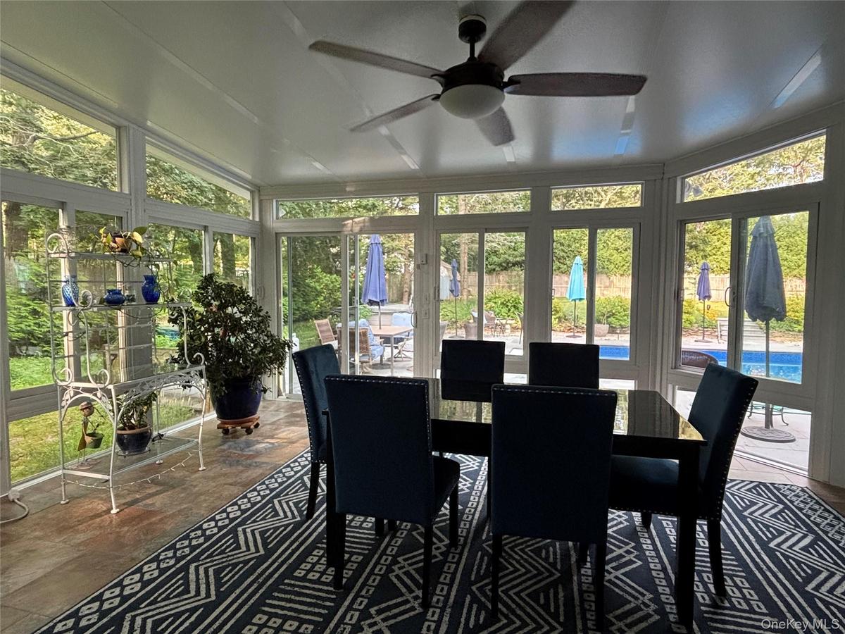 Sun room with extensive window panels, vaulted ceiling, Tiled flooring, a ceiling fan & A/C Unit
