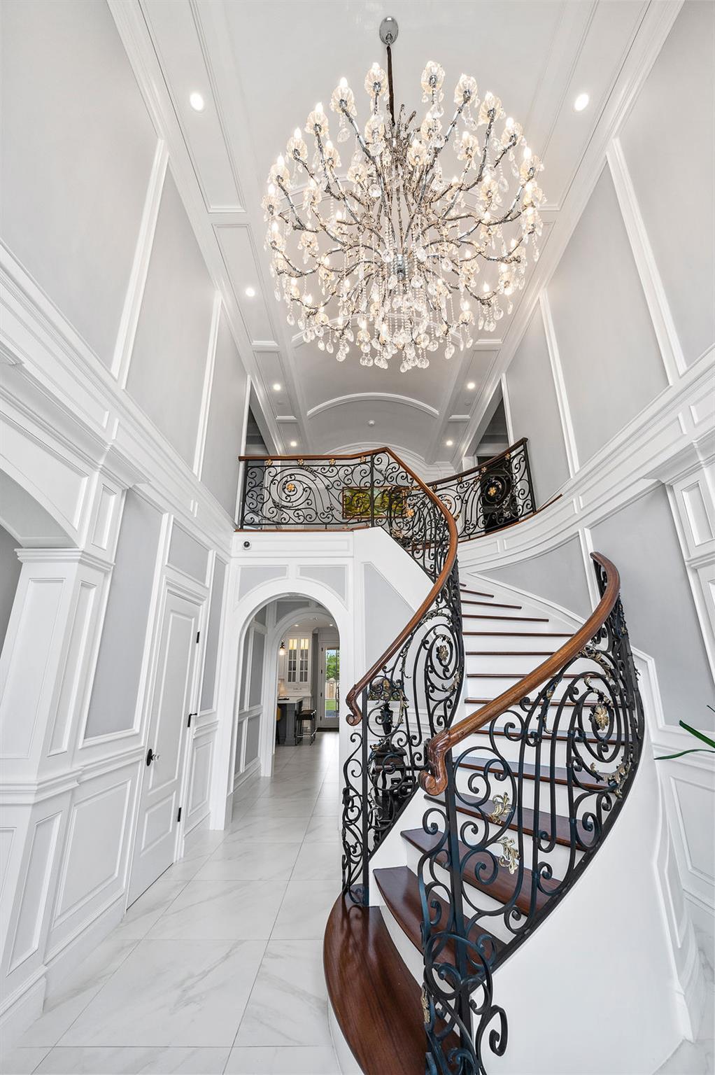Stairway featuring a decorative wall, a chandelier, arched walkways, recessed lighting, and marble finish floors
