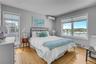 Bedroom featuring a wall mounted AC, multiple windows, light wood-type flooring, and a baseboard radiator