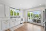 Kitchen with white cabinets, freestanding refrigerator, light stone counters, light wood-style flooring, and tasteful backsplash