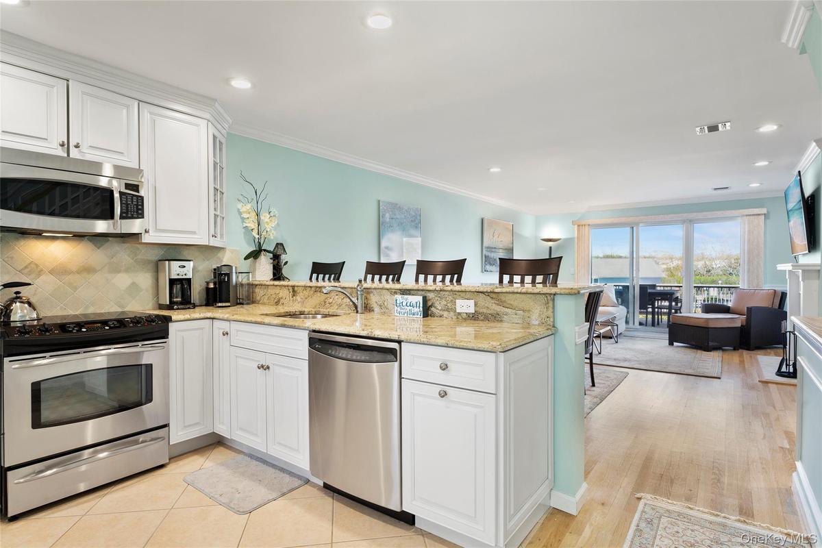 Kitchen featuring white cabinets, stainless steel appliances, a peninsula, a sink, and a breakfast bar area