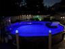 Outdoor pool featuring bright blue water, perimeter lighting, a deck surround, and a nearby pergola