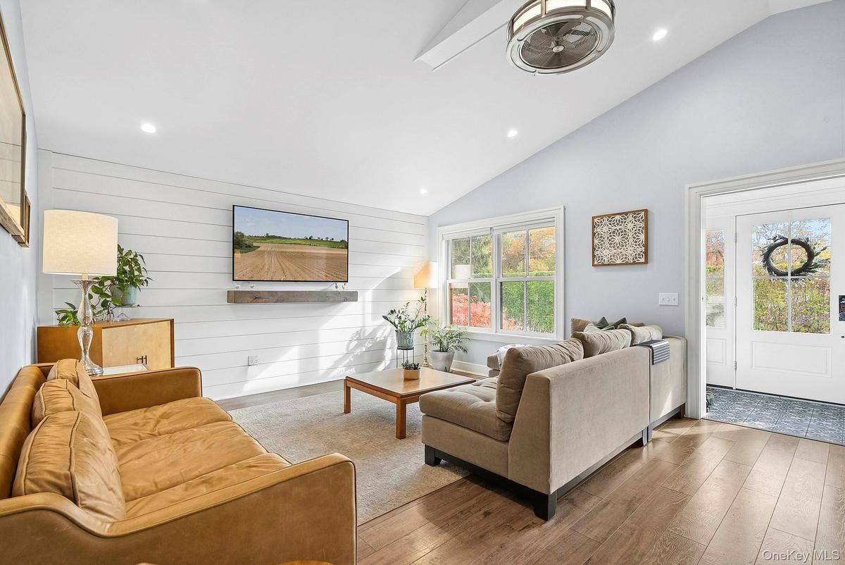 Living area with wood walls, recessed lighting, wood-type flooring, and high vaulted ceiling