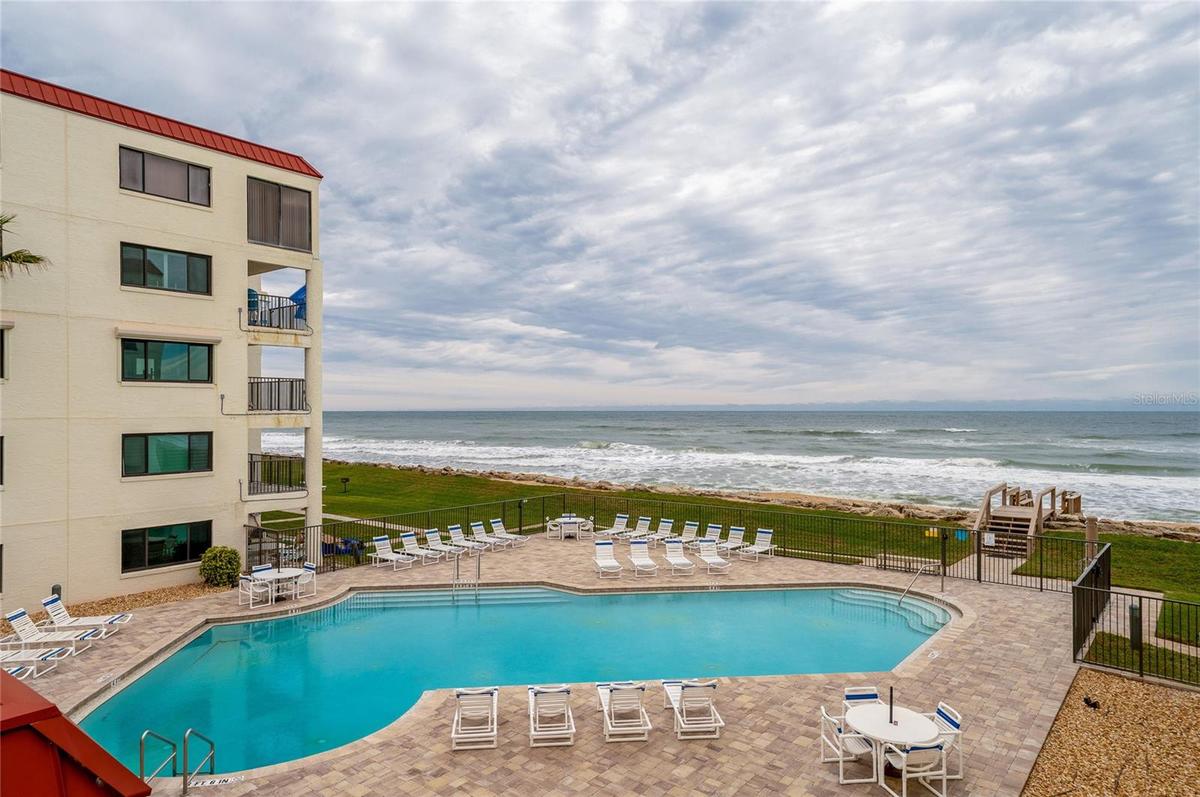 The oceanfront pool area features ample seating, a paved sun deck, and gated access to the beach—designed for relaxing and recreation.