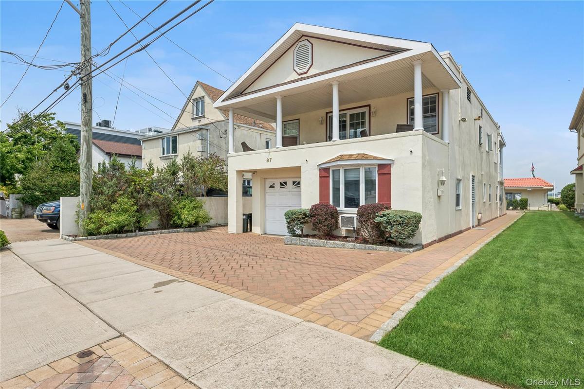 View of front of house with cooling unit, a balcony, a garage, and a front yard