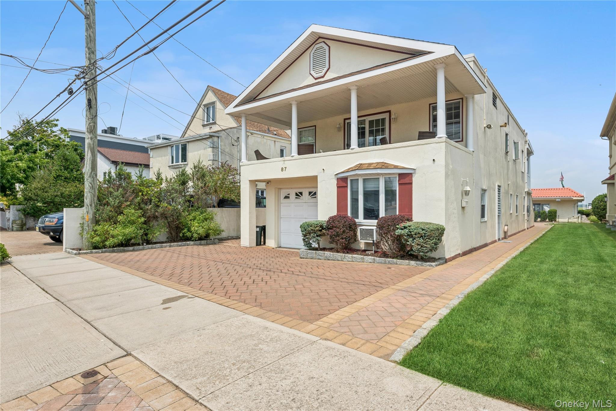 View of front of house with cooling unit, a balcony, a garage, and a front yard