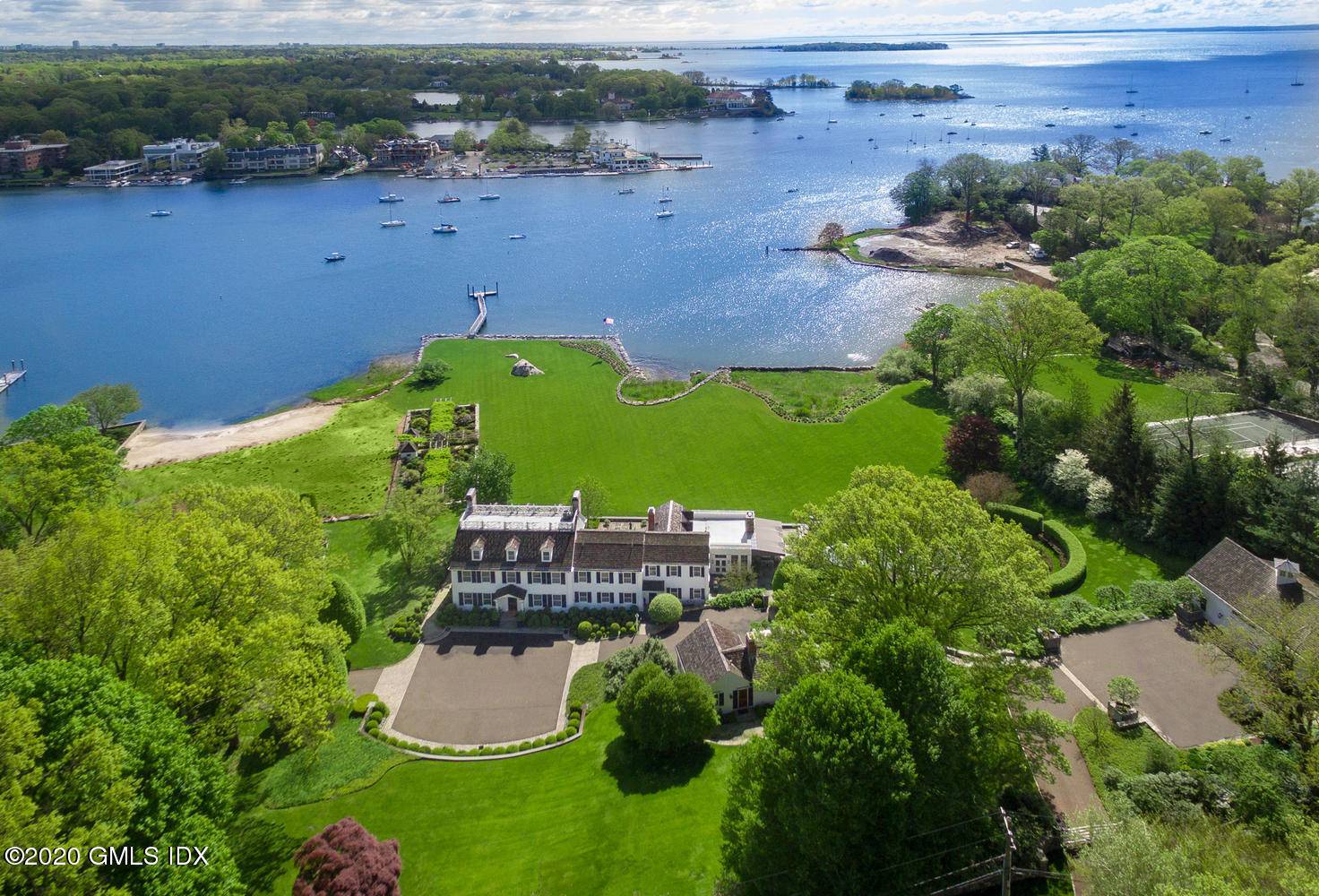 Magnificent waterfront estate embraces six exquisitely sculptured acres on a private road with heated pool, guest cottage, oak paneled barn, gorgeous gardens, dock and extensive shoreline on Greenwich Harbor.