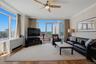 Spacious living area featuring expansive floor-to-ceiling windows, wood-finish flooring, and crown molding