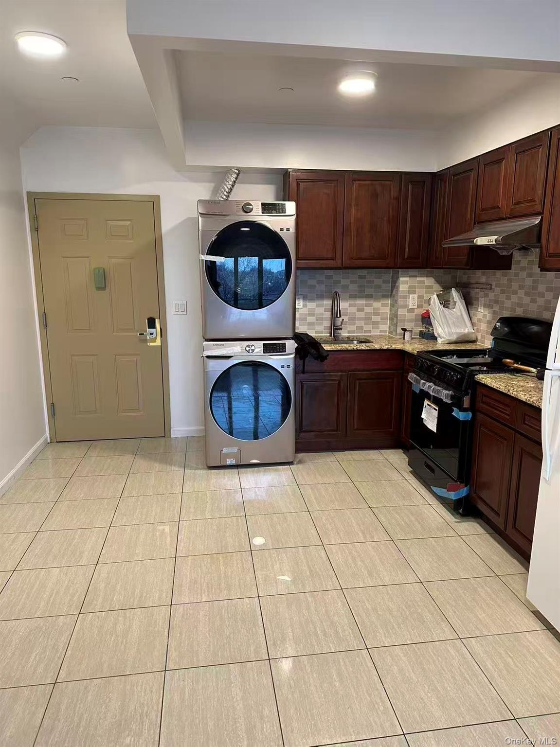 Kitchen with backsplash, black range with gas stovetop, light tile patterned floors, dark brown cabinets, and recessed lighting