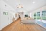 Living area featuring vaulted ceiling, light wood-style floors, healthy amount of natural light, a ceiling fan, and stairs