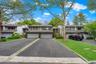 Contemporary multi-level residence featuring a two-car garage, asphalt driveway, mature tree landscaping, and a manicured lawn