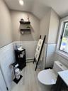 Light wood-finish flooring, white subway tile wainscoting, and a window for natural light