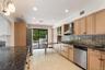 Kitchen featuring wood cabinetry, stainless steel appliances, dark stone countertops, tile flooring, and sliding glass doors to the exterior