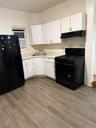 Kitchen with refrigerator, stove, white cabinets, light countertops, and extractor fan
