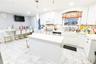 Kitchen featuring white cabinets, white appliances, crown molding, a center island, and pendant lighting