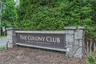Stone pillar entrance sign for "The Colony Club" featuring integrated lighting and natural landscaping