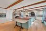 Kitchen with a breakfast bar area, white cabinets, a kitchen island, glass insert cabinets, and a stone fireplace