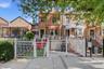 Brick facade residence featuring a white decorative metal fence and gate, an awning over the front entrance, and an additional white awning over the b