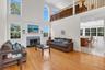 Two-story living area with hardwood flooring, a fireplace featuring a stone surround and hearth, and an upper-level railing overlooking the living roo
